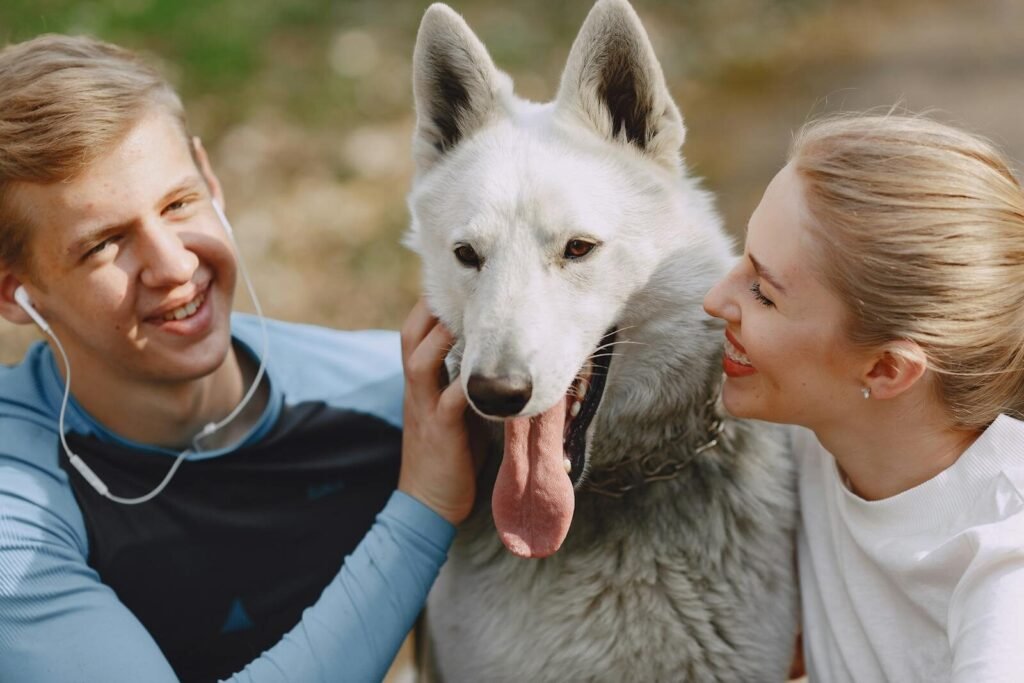 A joyful couple enjoying time with their white dog in an outdoor setting, showcasing love and companionship.